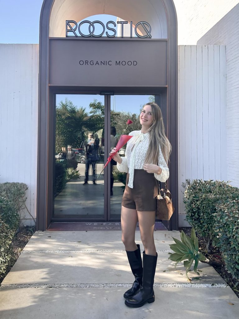 Blanca Guerrero con blusa clara y botas negras frente a Roostiq